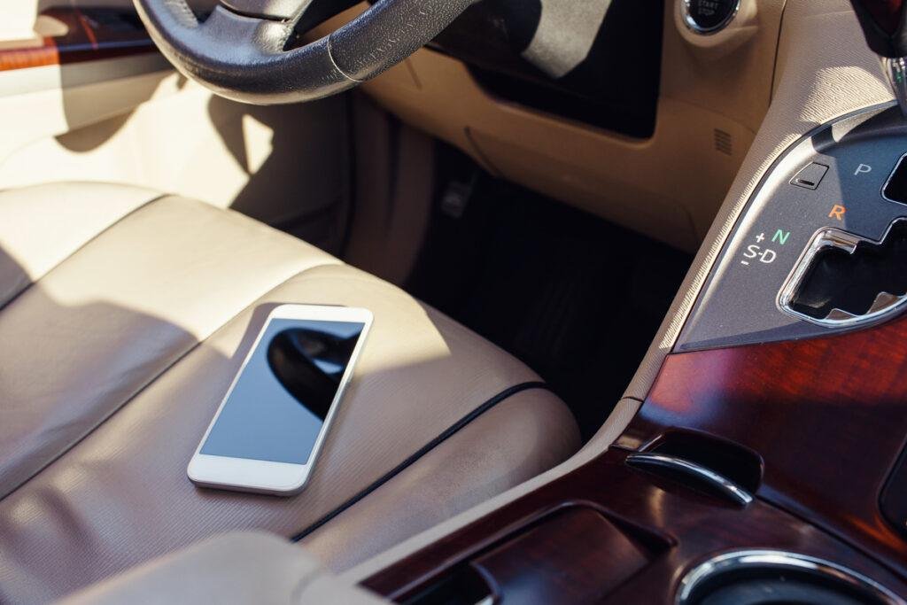 Foto de um celular sobre o banco de um carro representando o risco de deixar o celular exposto ao sol