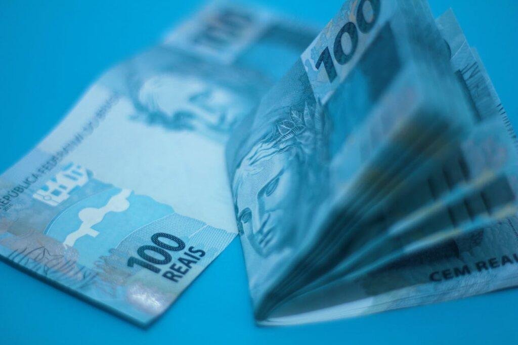 Notas de 100 reais representando prompts para organização financeira para gerir aumento salarial