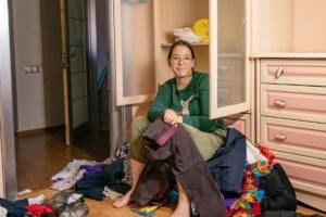 garota se senta em uma pilha de coisas jogadas fora do armário