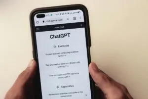 Close de uma mão segurando um celular. Na tela o app ChatGPT